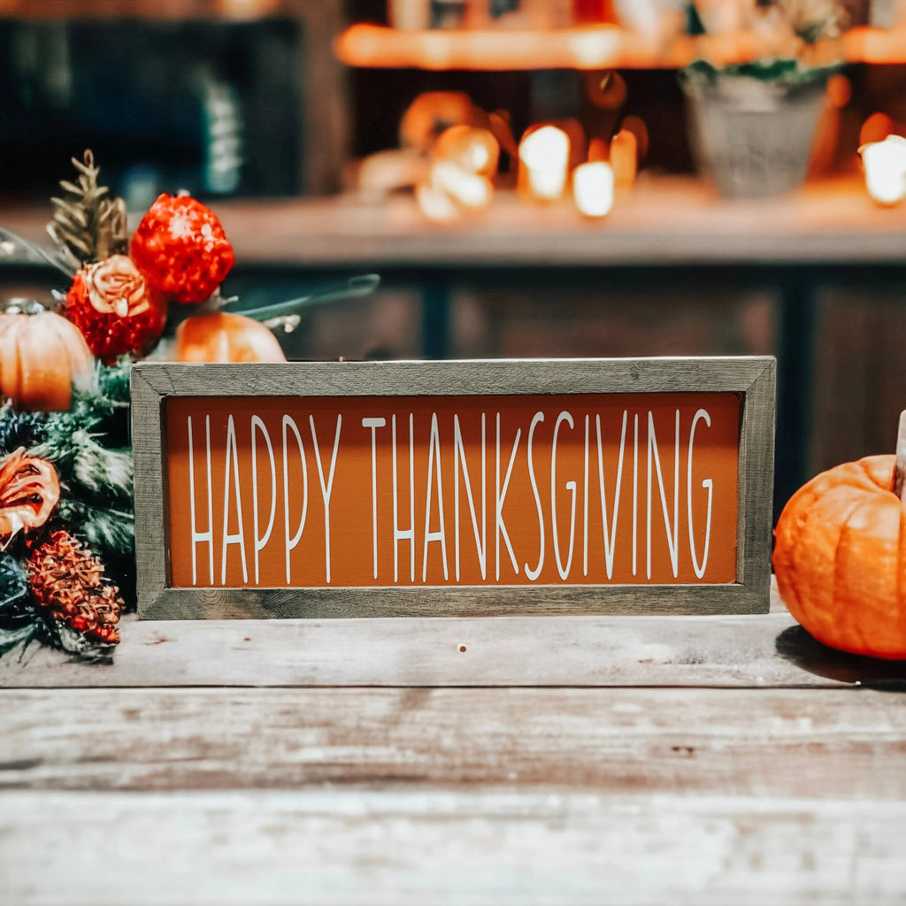 Rustic Happy Thanksgiving orange wood sign with grey frame on white wood mantel with orange flowers and pumpkins by fireplace
