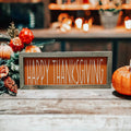 Rustic Happy Thanksgiving orange wood sign with grey frame on white wood mantel with orange flowers and pumpkins by fireplace