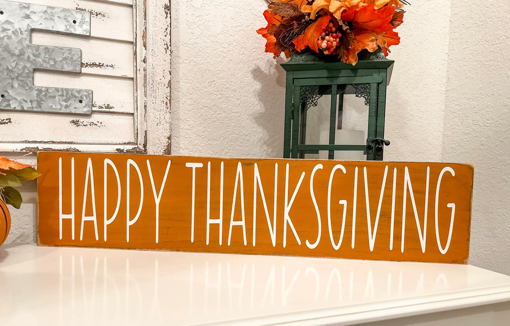 Happy Thanksgiving golden amber farmhouse wood sign with white hand-painted lettering free-standing on white console table with Give Thanks reversible block sign and fall floral lantern