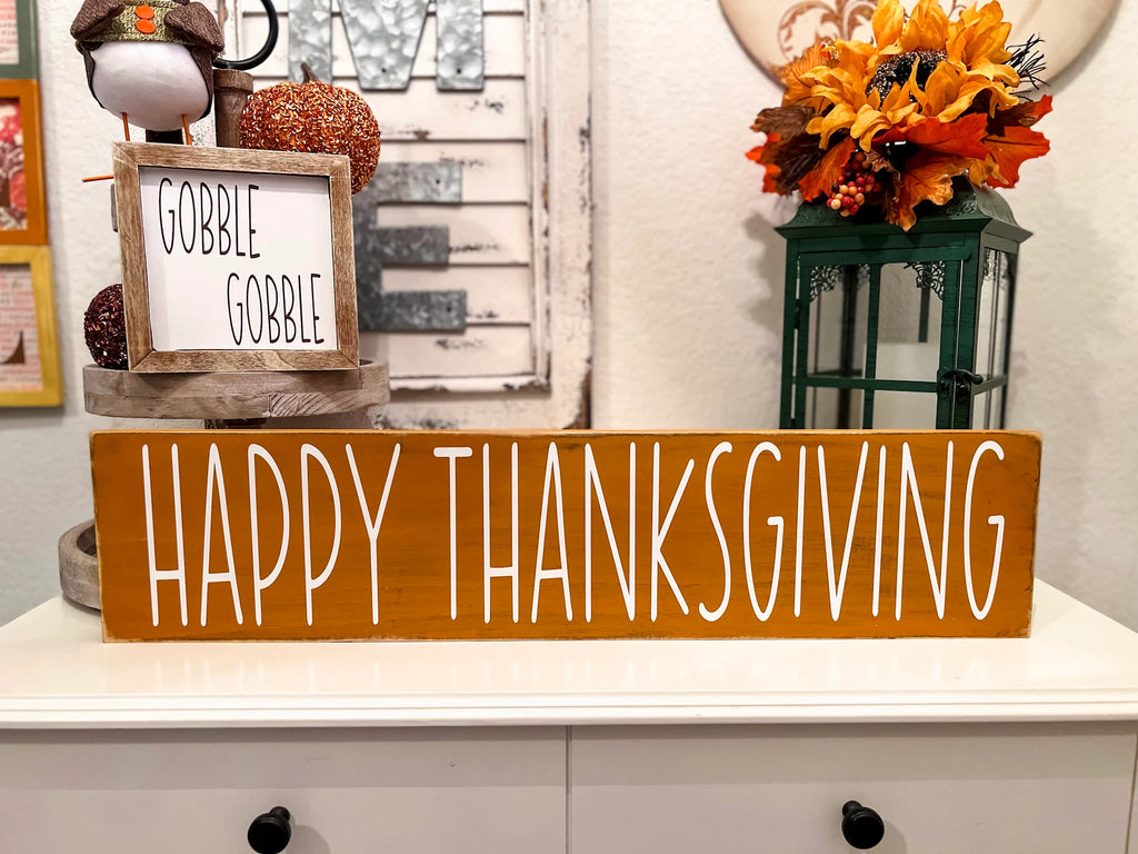 Happy Thanksgiving golden amber farmhouse wood sign with white hand-painted lettering free-standing on white console table with Gobble Gobble reversible block sign and fall floral lantern hero shot