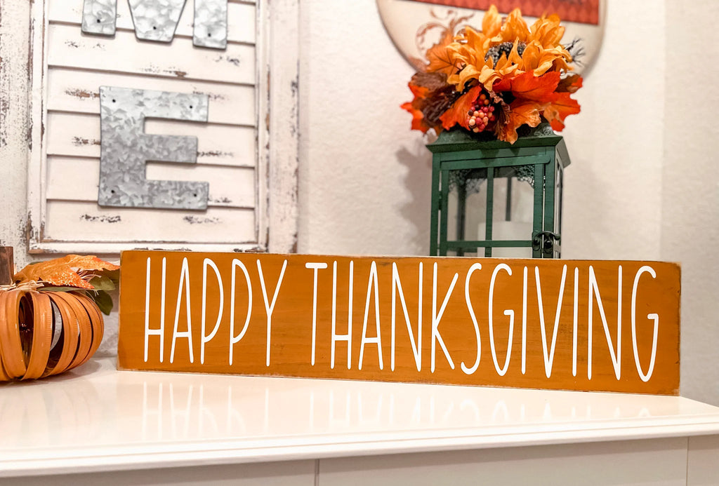 Happy Thanksgiving golden amber farmhouse wood sign with white hand-painted lettering free-standing on white console table product hero shot