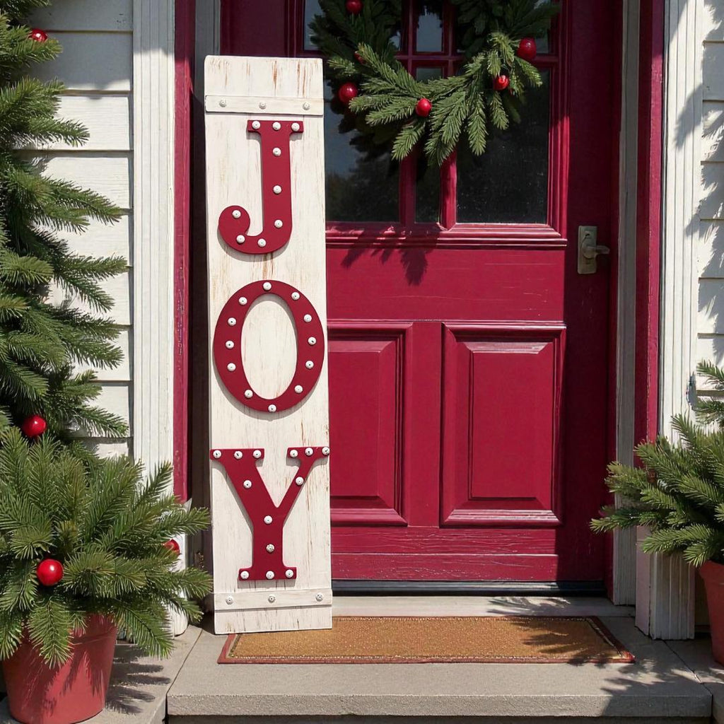 JOY porch leaner sign with red marquee letters leaning against gray front door with Christmas wreath and red bow
