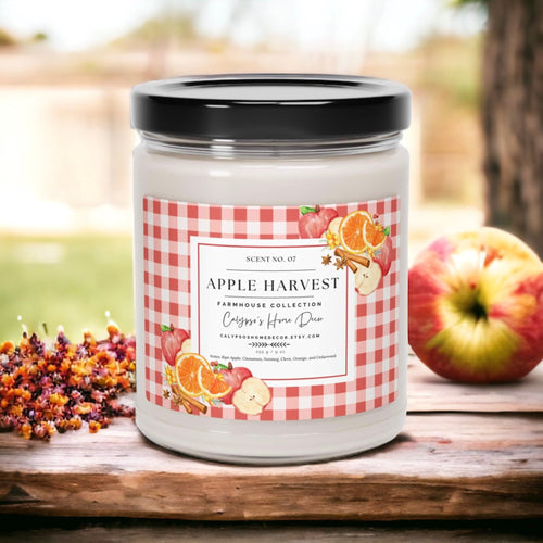 Apple Harvest candle on wood table with red apples and fall leaves by window