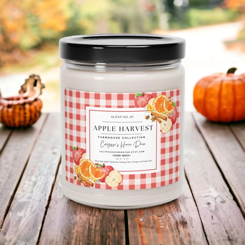 Apple Harvest candle on rustic wood table with red apples and autumn foliage background