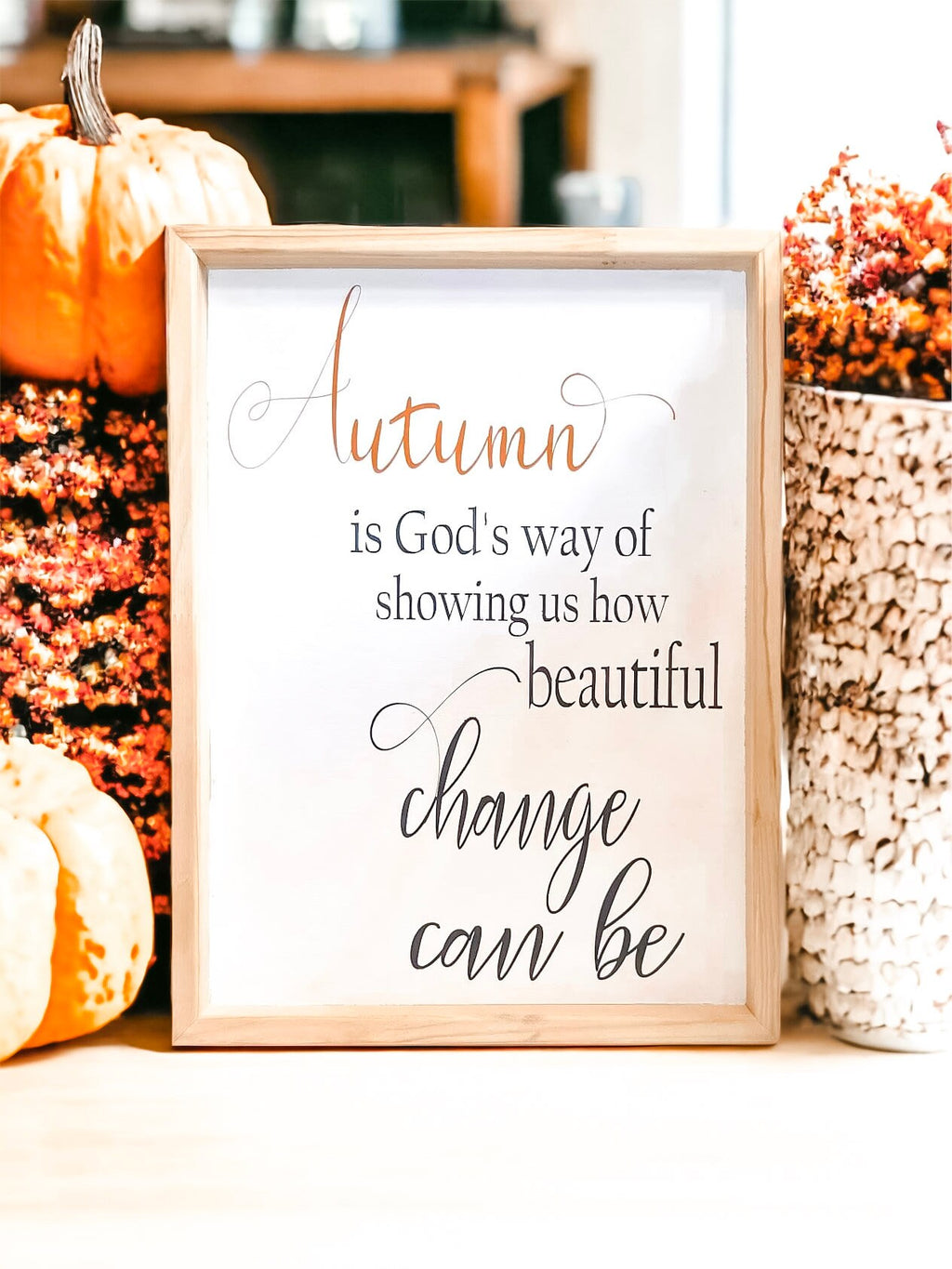Autumn is Gods Way framed wood sign with copper and black lettering in whitewashed birch frame on white surface with orange pumpkins and dried botanicals angled view