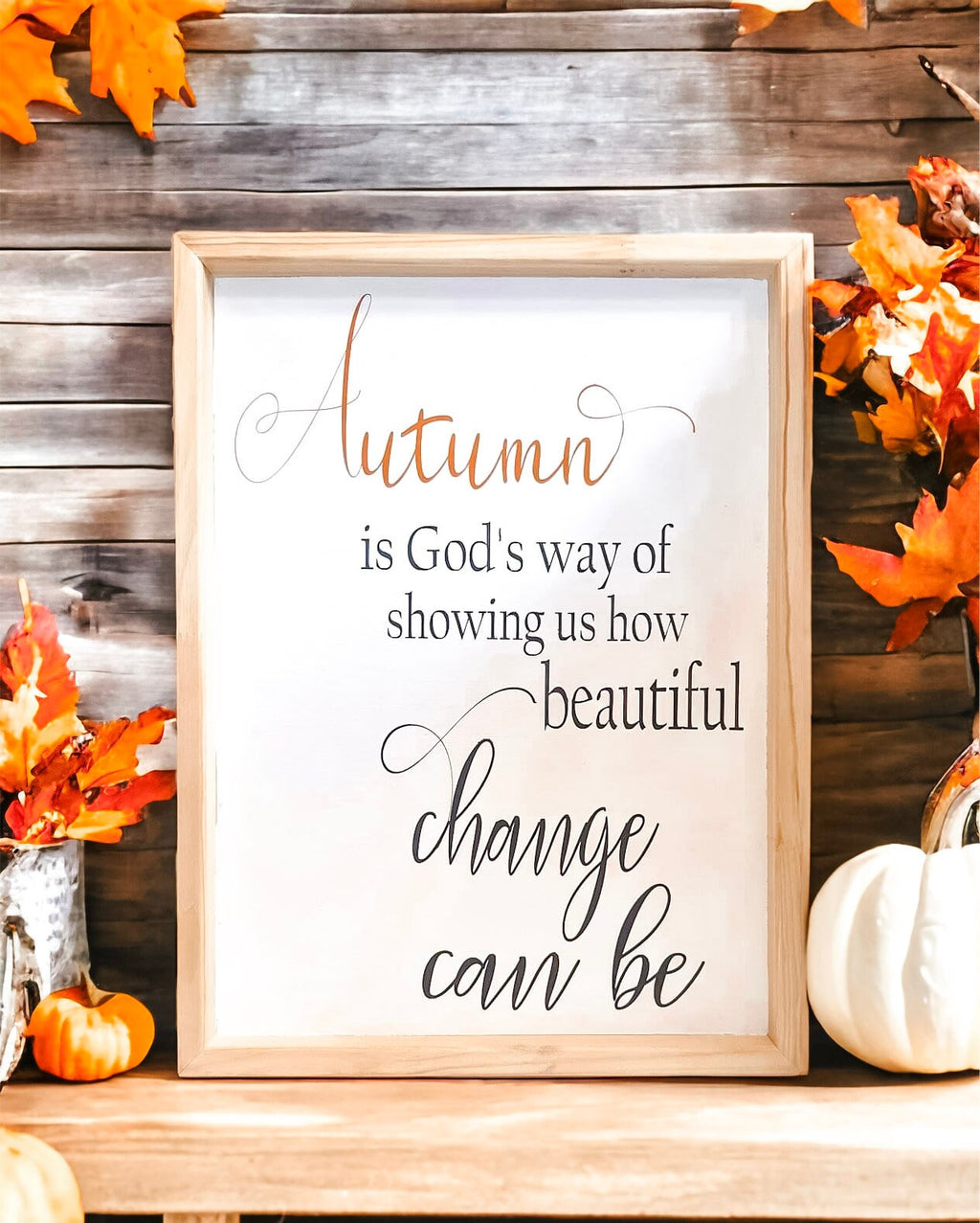 Autumn is Gods Way framed wood sign with copper and black lettering in whitewashed birch frame on white brick mantel with orange and white pumpkins in wicker basket