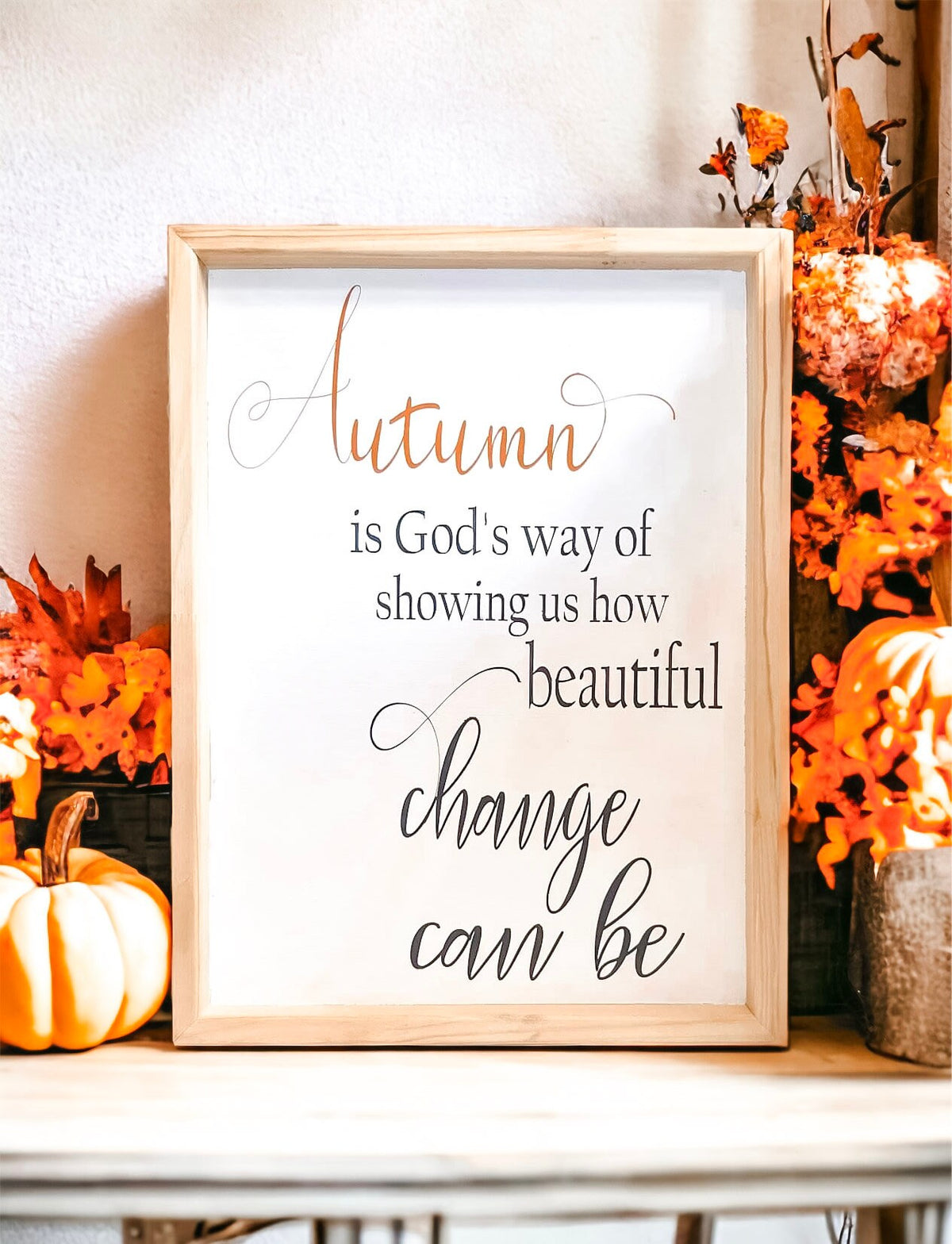 Autumn is Gods Way framed wood sign with copper and black lettering in whitewashed birch frame on white surface with orange and white pumpkins and textured vase