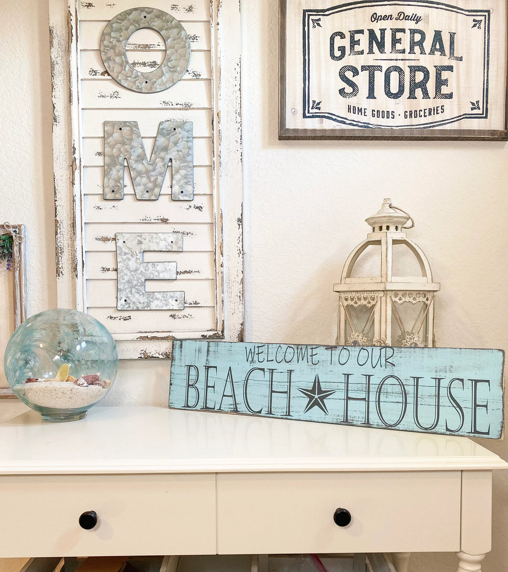 Welcome to Our Beach House reclaimed wood sign on white dresser with white hydrangeas and lantern