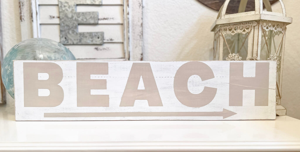 Reclaimed wood Beach arrow sign in distressed white with sandy taupe lettering on white console table with vintage lantern angled view