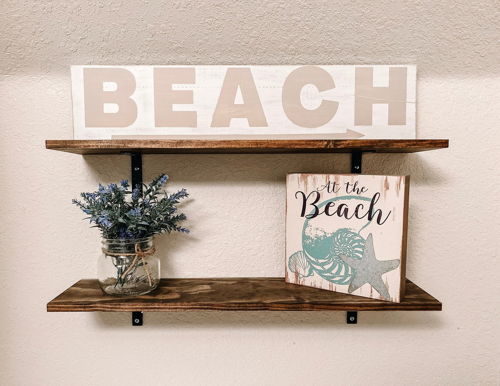 Reclaimed wood Beach arrow sign in distressed white with sandy taupe lettering on white console table with vintage lantern close up front view