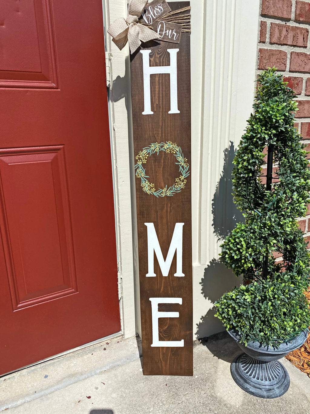 Bless Our Home porch leaner sign in dark walnut angled view against brick wall