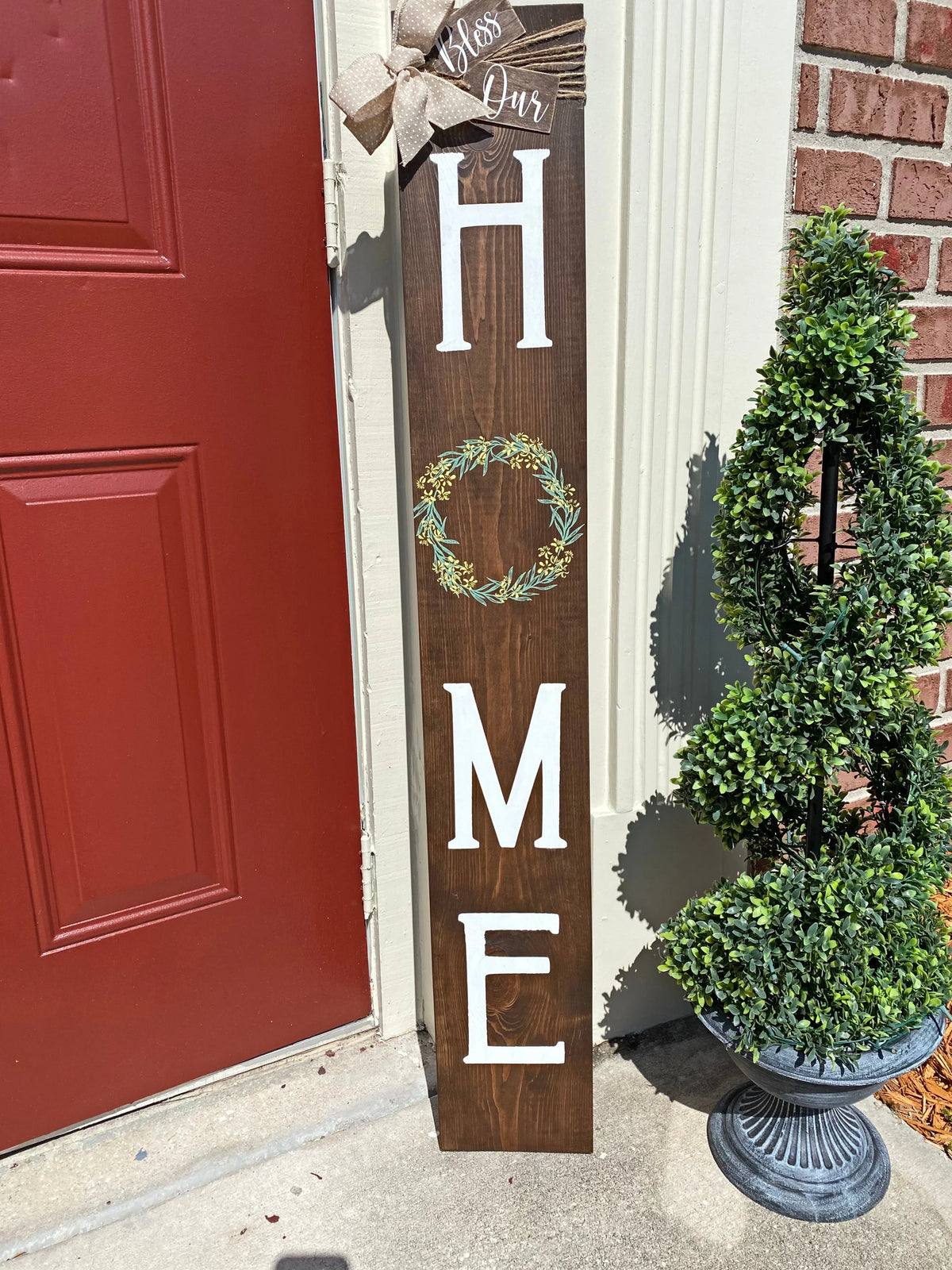 Bless Our Home porch leaner sign in dark walnut angled view against brick wall