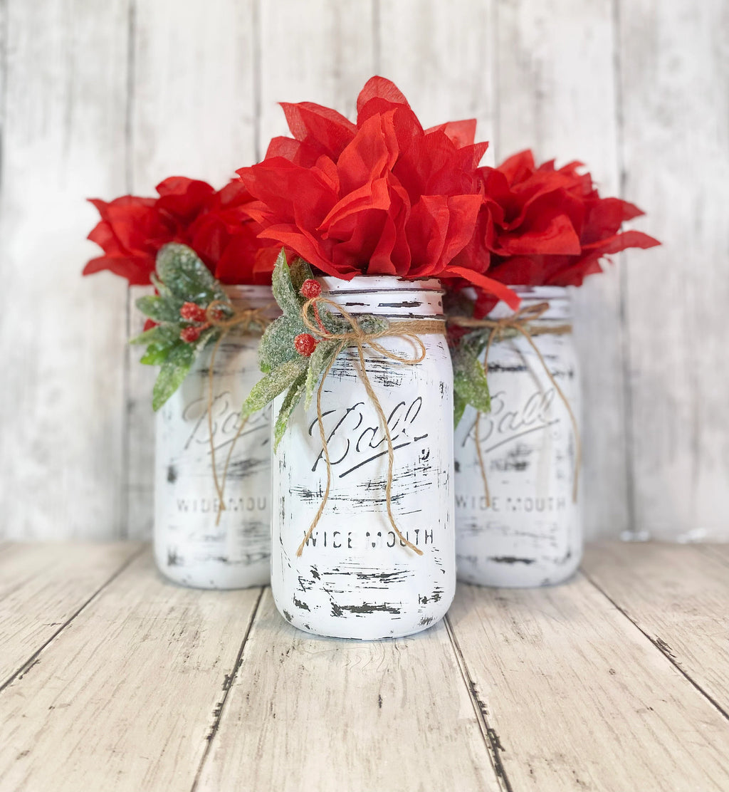 Close up of distressed white Ball mason jar with holly and jute bow