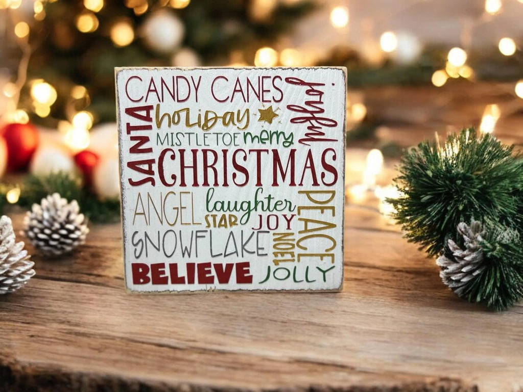 Christmas Favorites word block sign on snowy rustic wood mantel with pine garland and warm string lights with snow falling outside window
