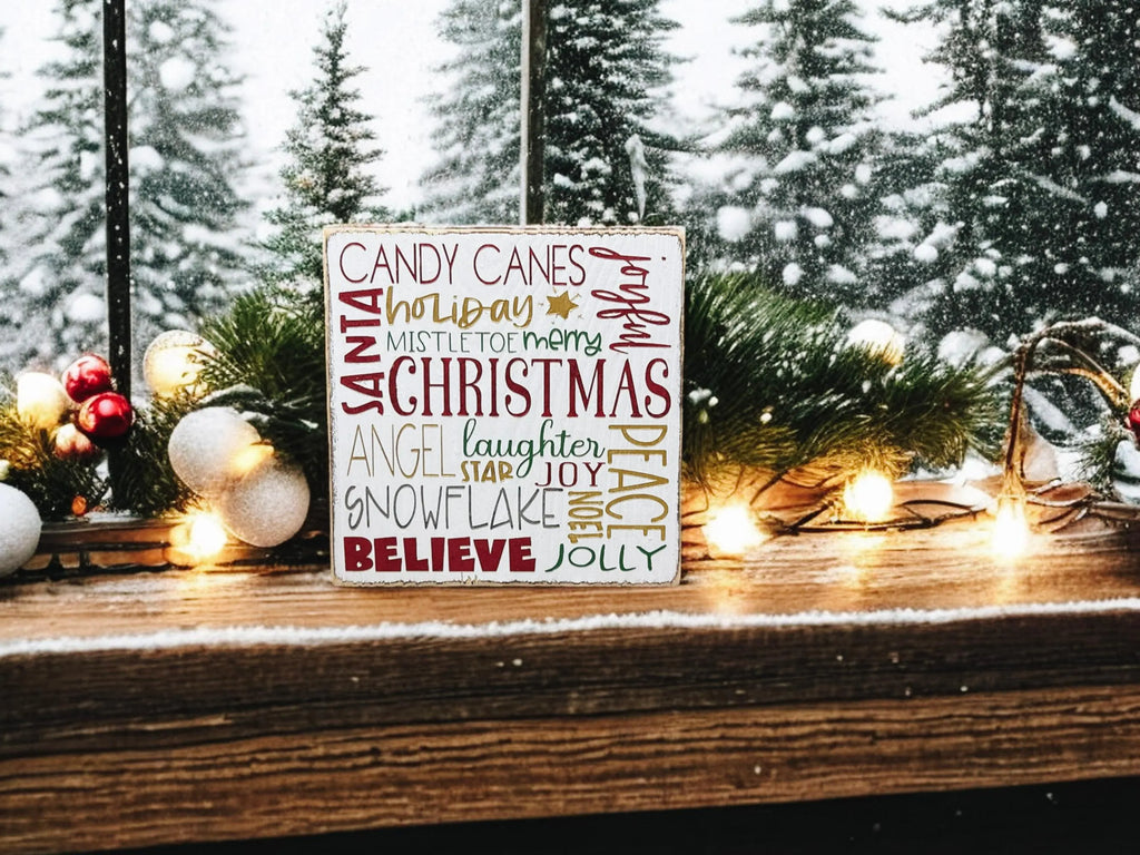 Christmas Favorites word block sign on rustic wood surface with pine cones and lit pine garland in warm light