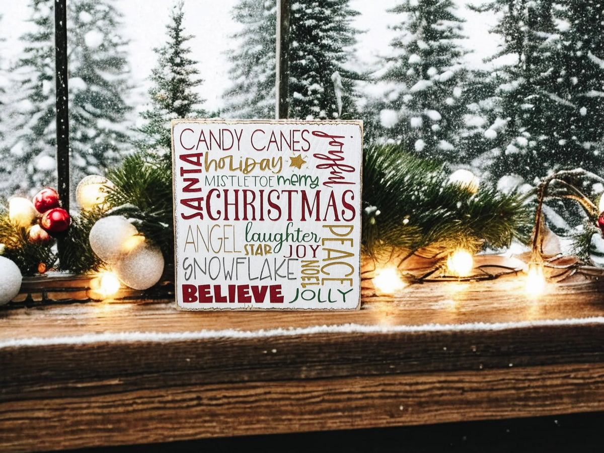 Christmas Favorites word block sign on rustic wood surface with pine cones and lit pine garland in warm light