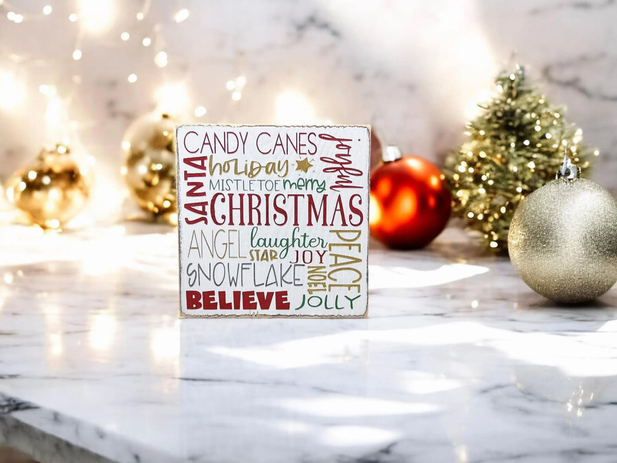 Christmas Favorites word block sign on white marble surface with red and gold glitter ornaments and bokeh string lights