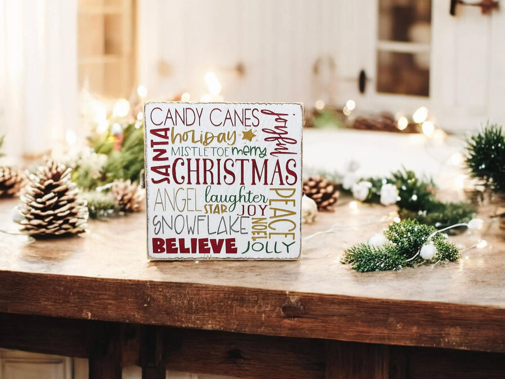 Christmas Favorites word block sign on granite countertop with pine cones and lit mini Christmas tree in background
