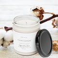 Clean Cotton soy candle Scent No. 02 Farmhouse Collection lit on white wood surface with cotton stems in background