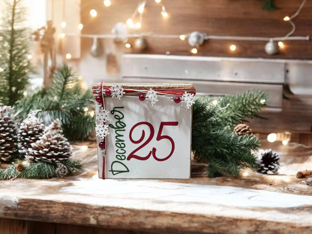 December 25 Christmas wood block sign with red 25 and green December script jute top and snowflake bead garland on rustic wood spool tray with red and silver ornaments and pine sprigs tiered tray styling