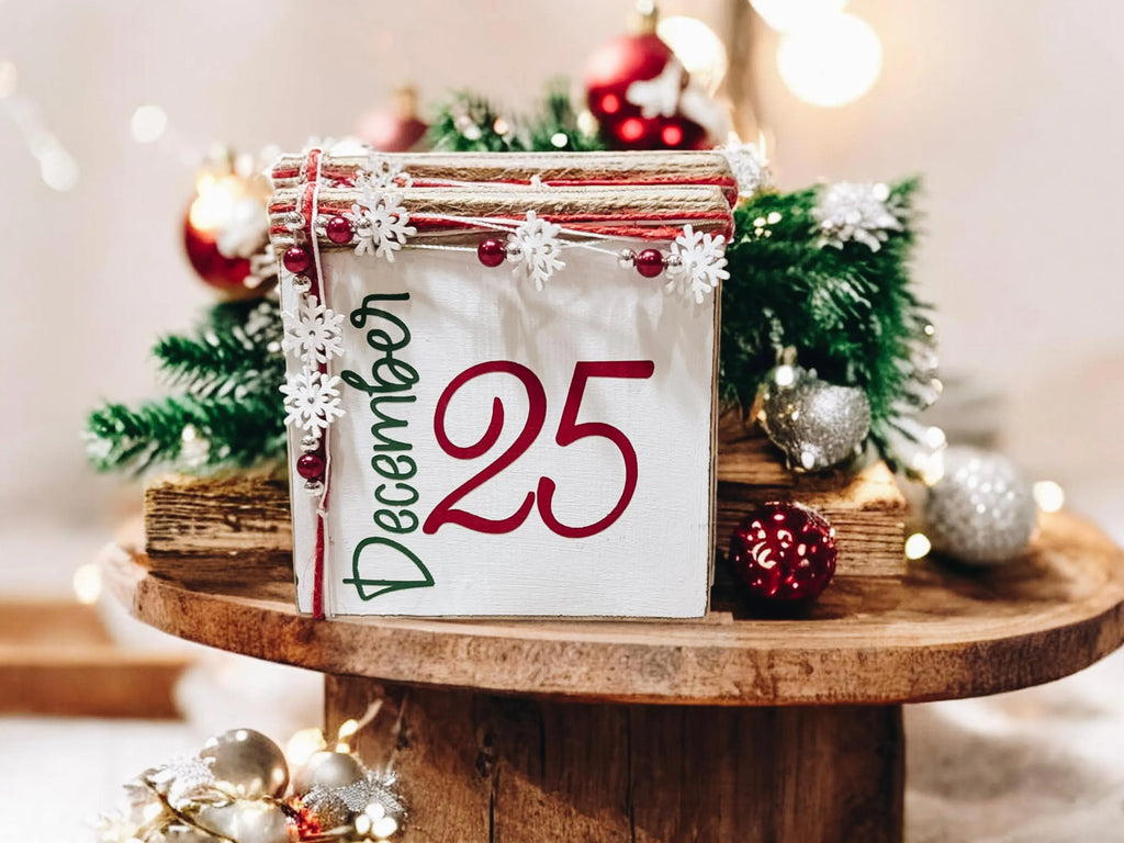 December 25 Christmas wood block sign with red 25 and green December script jute top and snowflake bead garland product hero shot on white background