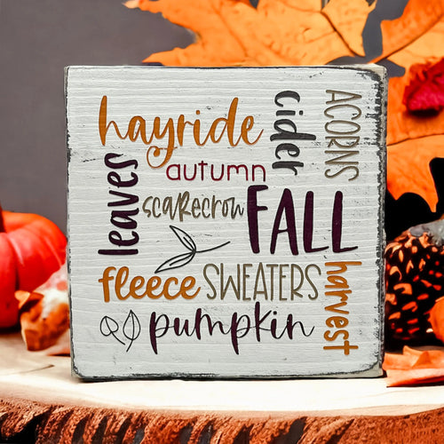 Fall Favorites word cloud wood block sign on wood dining table with white flowers and vase in background