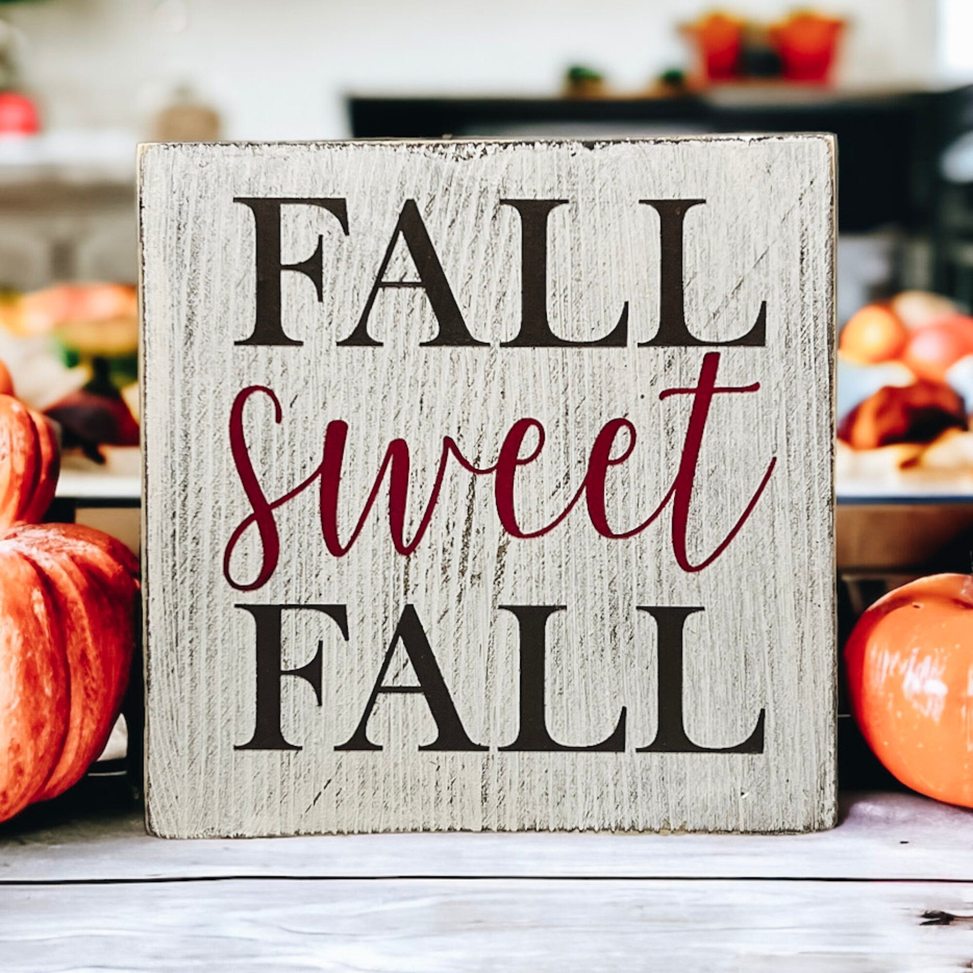 Fall Sweet Fall distressed white wood block sign on white counter with orange pumpkins brownies and white cake