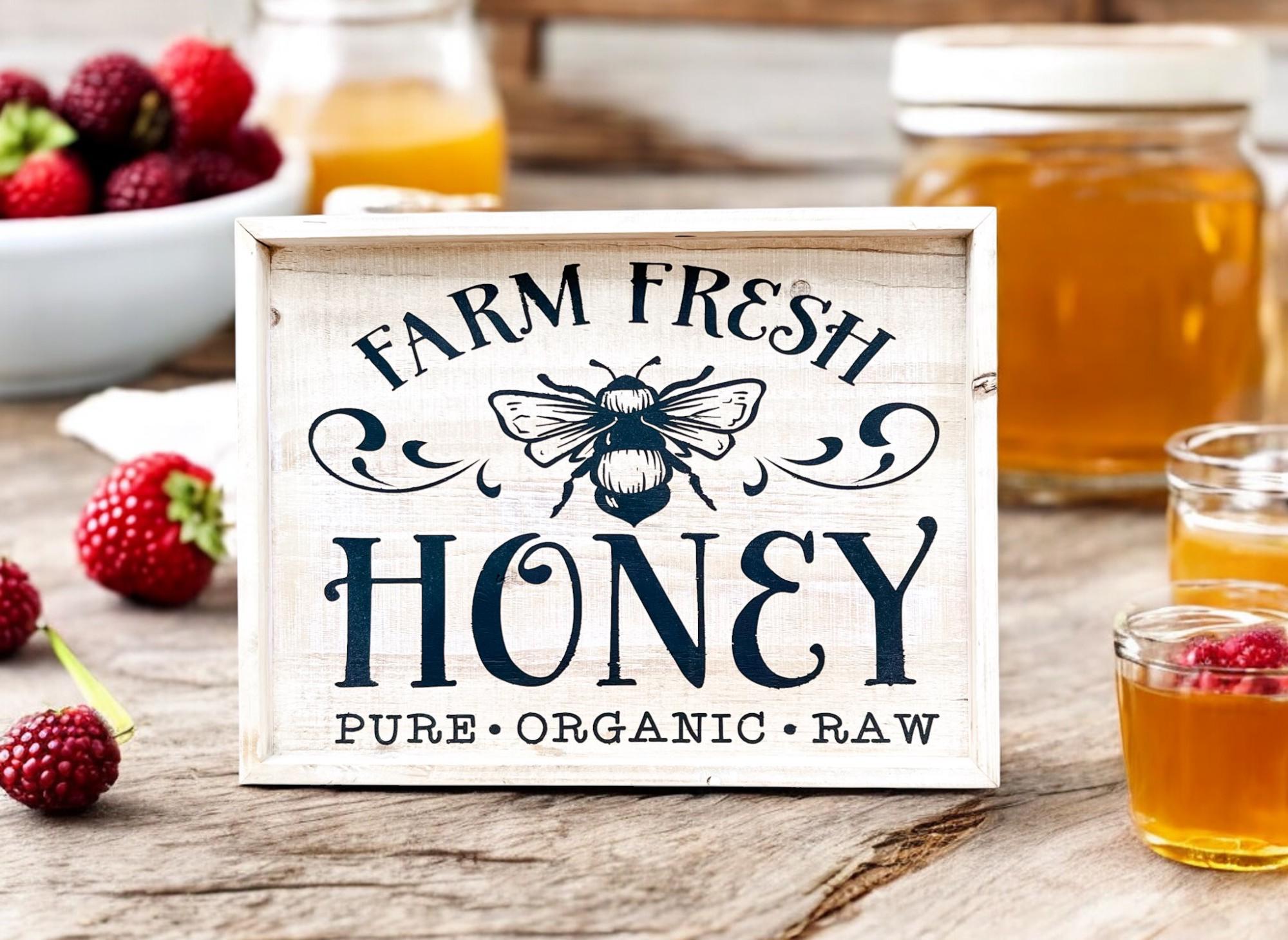 Farm Fresh Honey framed reclaimed wood sign with navy bee graphic and chalk paste lettering in distressed whitewash frame on farmhouse kitchen counter with white pitchers and copper canister