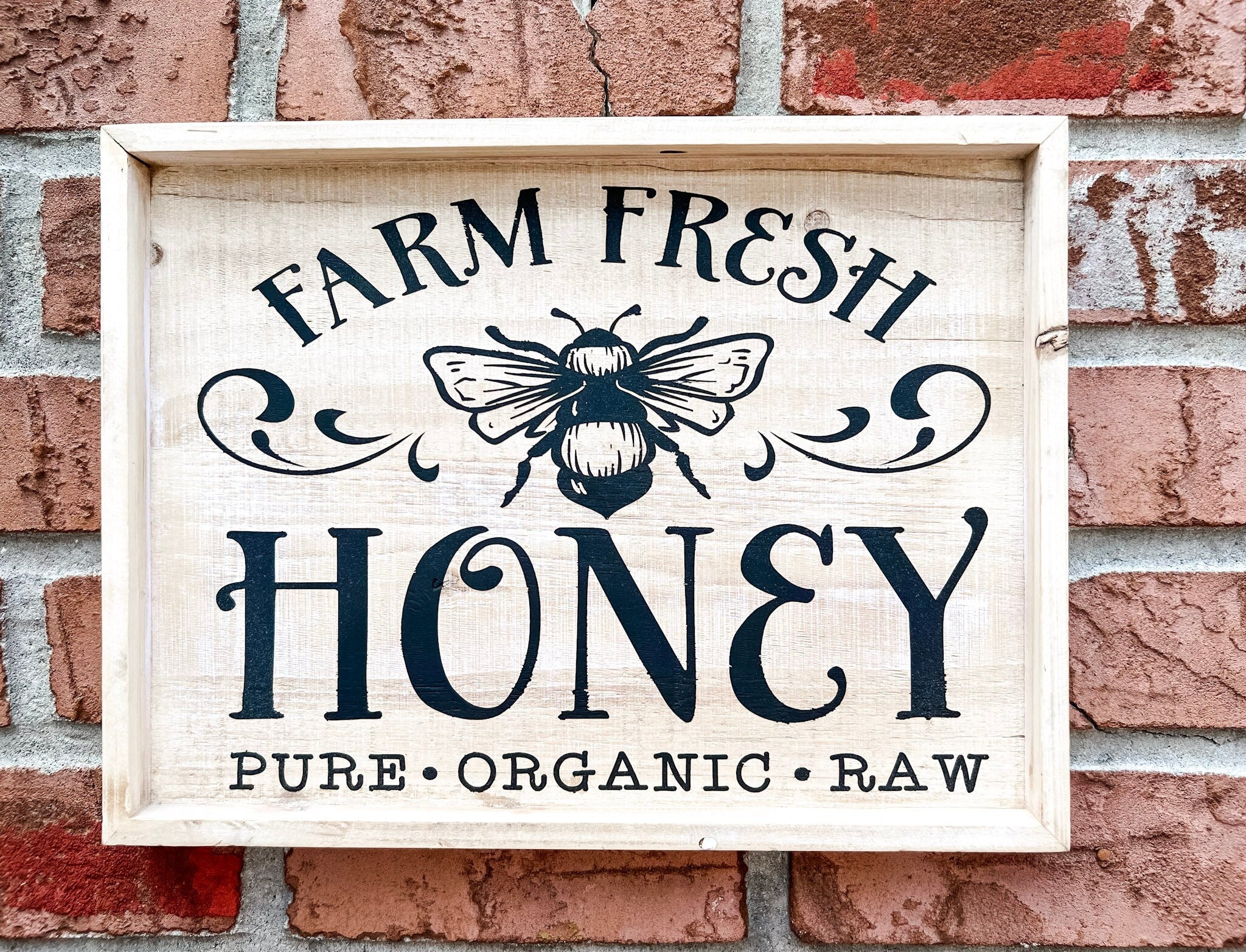 Farm Fresh Honey framed reclaimed wood sign with navy bee graphic and chalk paste lettering in distressed whitewash frame on rustic wood surface with honey jars strawberries and raspberries lifestyle shot