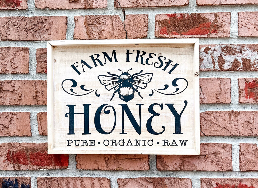 Farm Fresh Honey framed reclaimed wood sign with navy bee graphic and chalk paste lettering in distressed whitewash frame on rustic wood surface hero shot