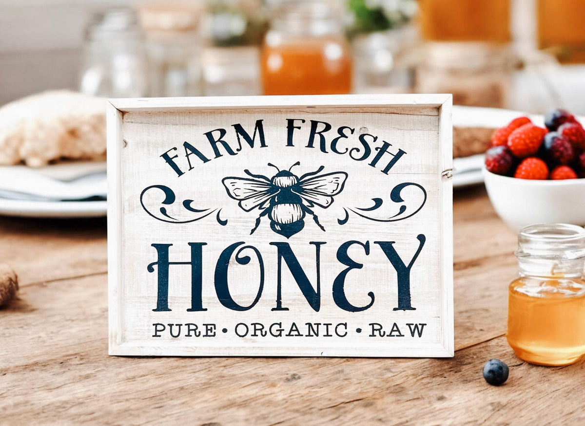 Farm Fresh Honey framed reclaimed wood sign with navy bee graphic and chalk paste lettering in distressed whitewash frame on rustic wood surface product hero shot
