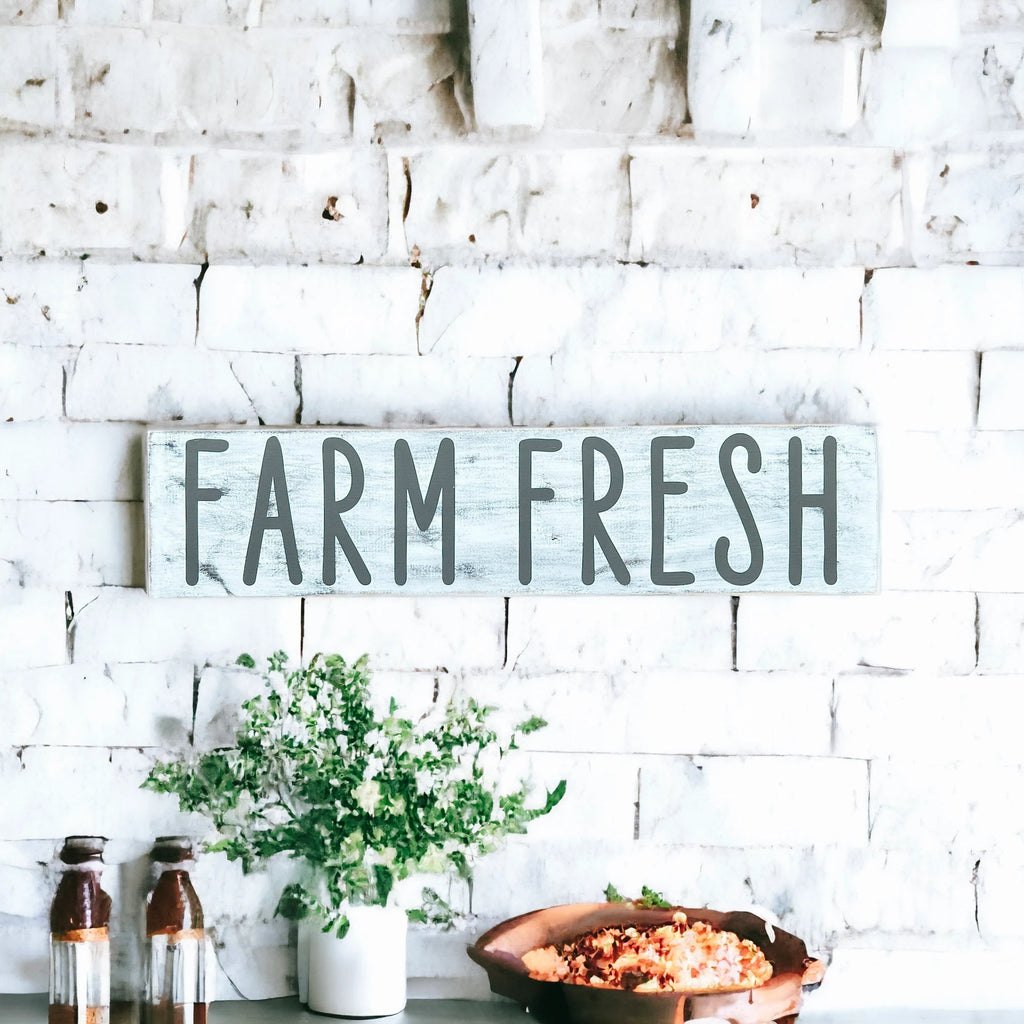 Farm Fresh distressed white wood sign with dark grey lettering on white marble counter angled view
