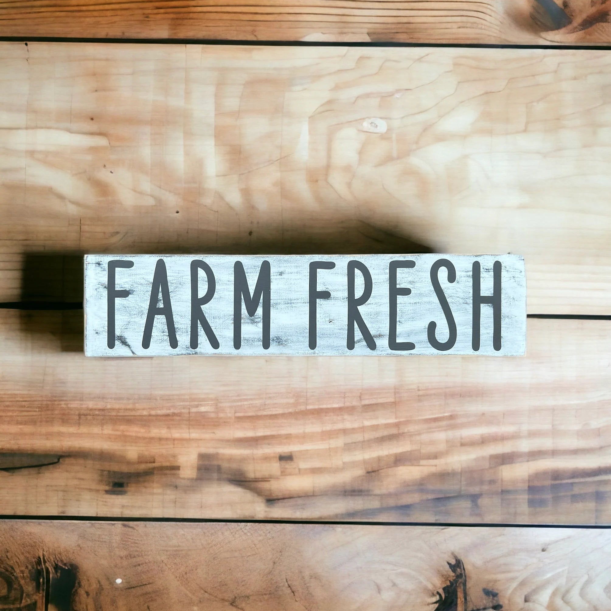 Farm Fresh distressed white wood sign with dark grey lettering hung on white brick wall above kitchen counter with white flowers and mason jars