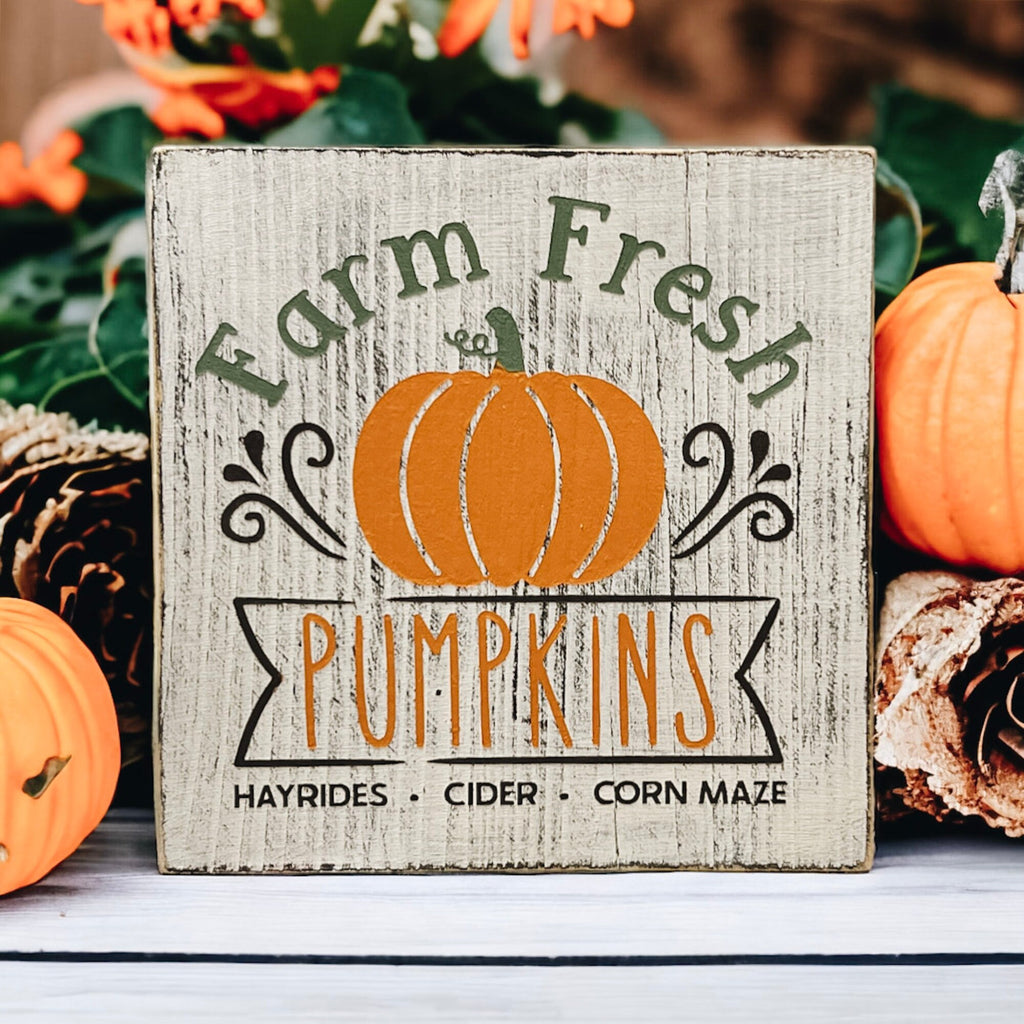 Farm Fresh Pumpkins wood block sign on white tiered tray with orange pumpkins and pinecones