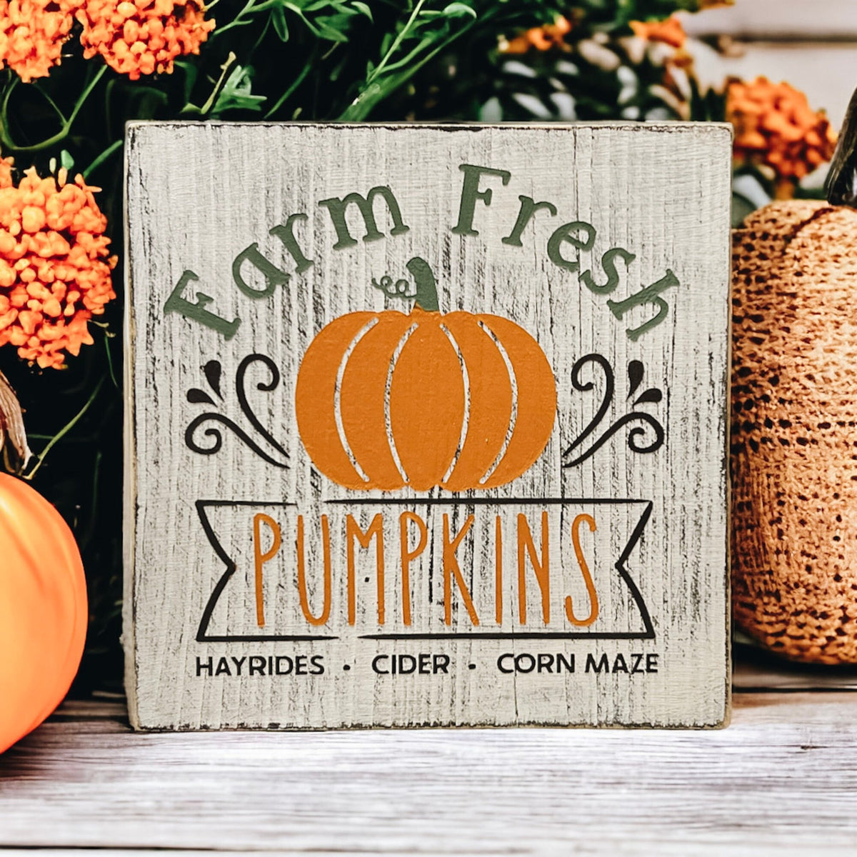 Farm Fresh Pumpkins wood block sign with orange pumpkins and pinecones on white surface