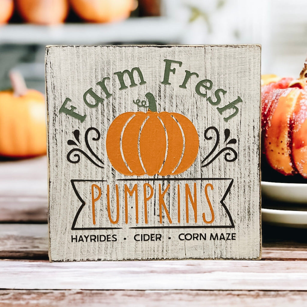 Farm Fresh Pumpkins wood block sign front view on white surface with fall pumpkin arrangement