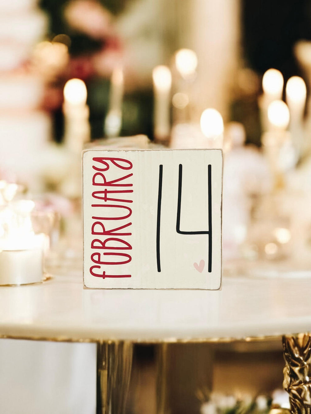 February 14 sign on white lace tablecloth with pillar candles and white roses