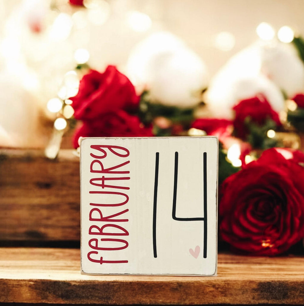 February 14 sign on marble cake stand with candles and romantic candlelit setting
