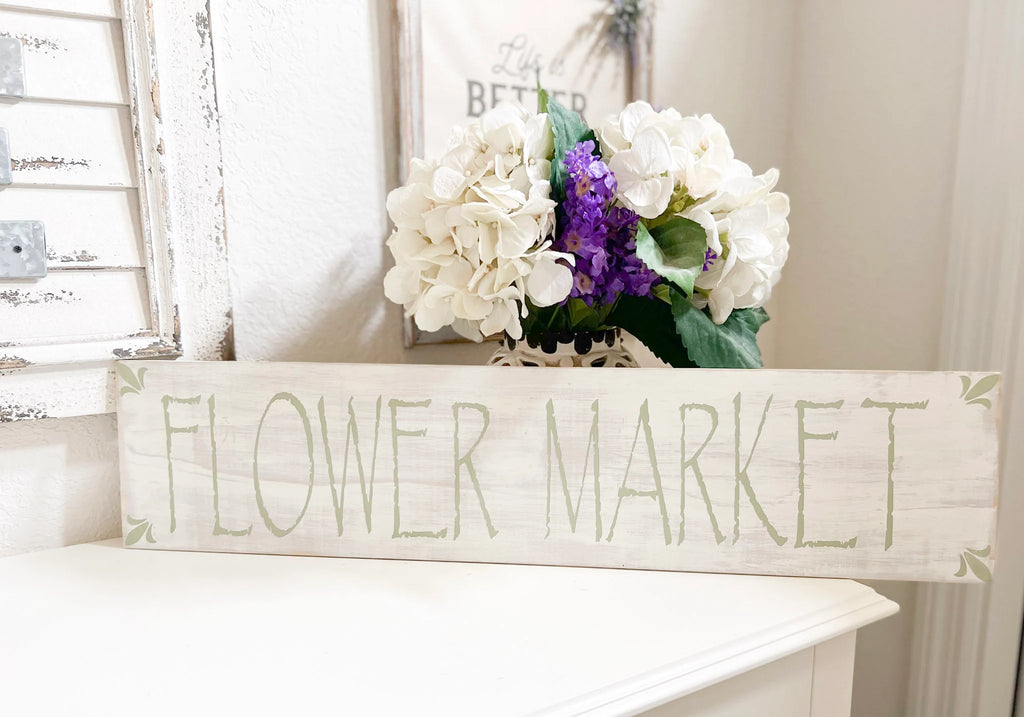 Flower Market wood sign with sage green lettering on white mantle with hydrangeas and purple flowers