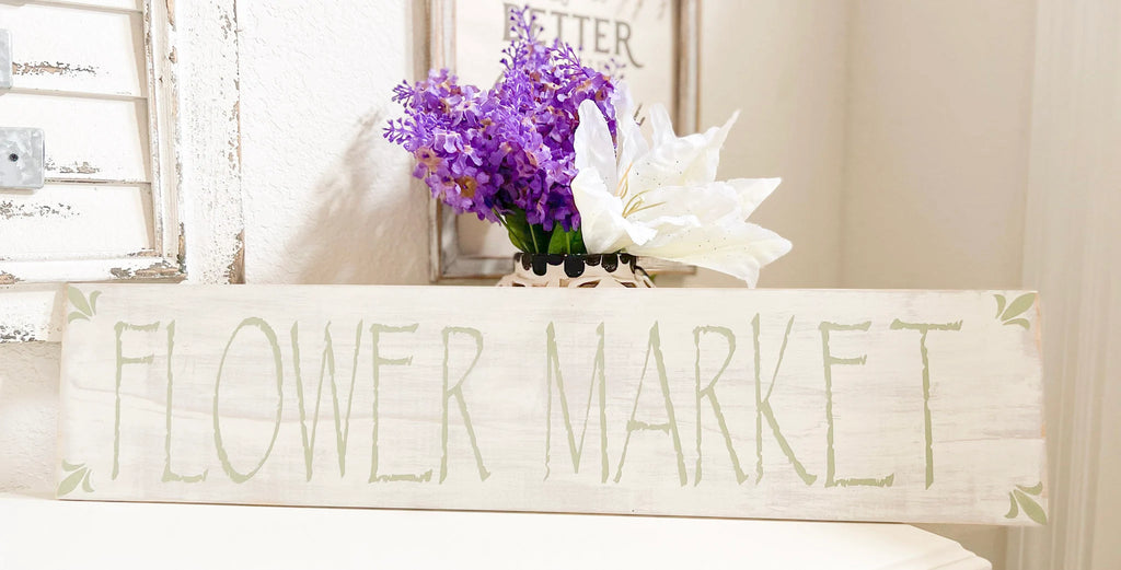 Flower Market sign on white surface with purple flowers and shutter backdrop