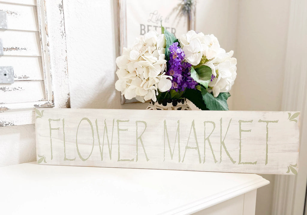 Flower Market sign on white surface with lantern and hydrangea arrangement