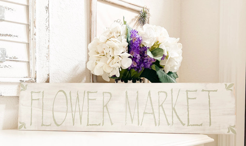 Flower Market sign close up with sage green lettering and lily flowers