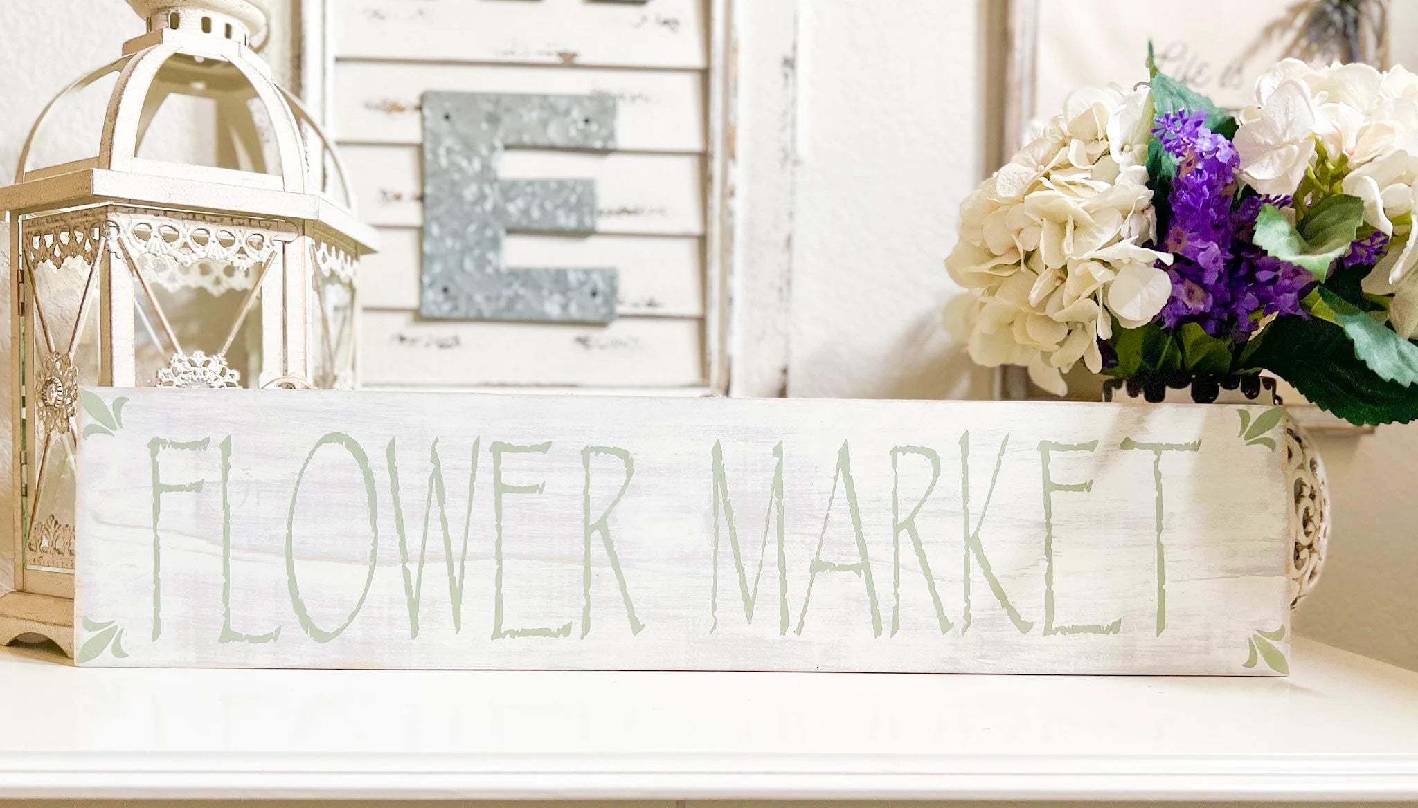 Flower Market sign on white mantle with purple and white lily arrangement