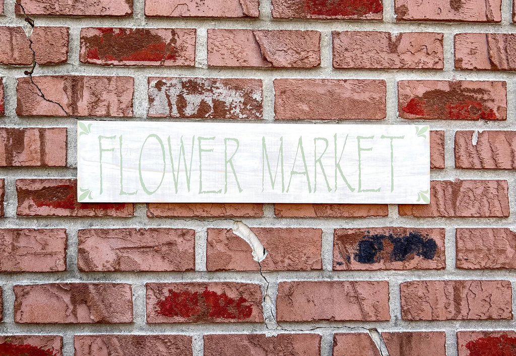 Flower Market sign mounted on red brick wall outdoors