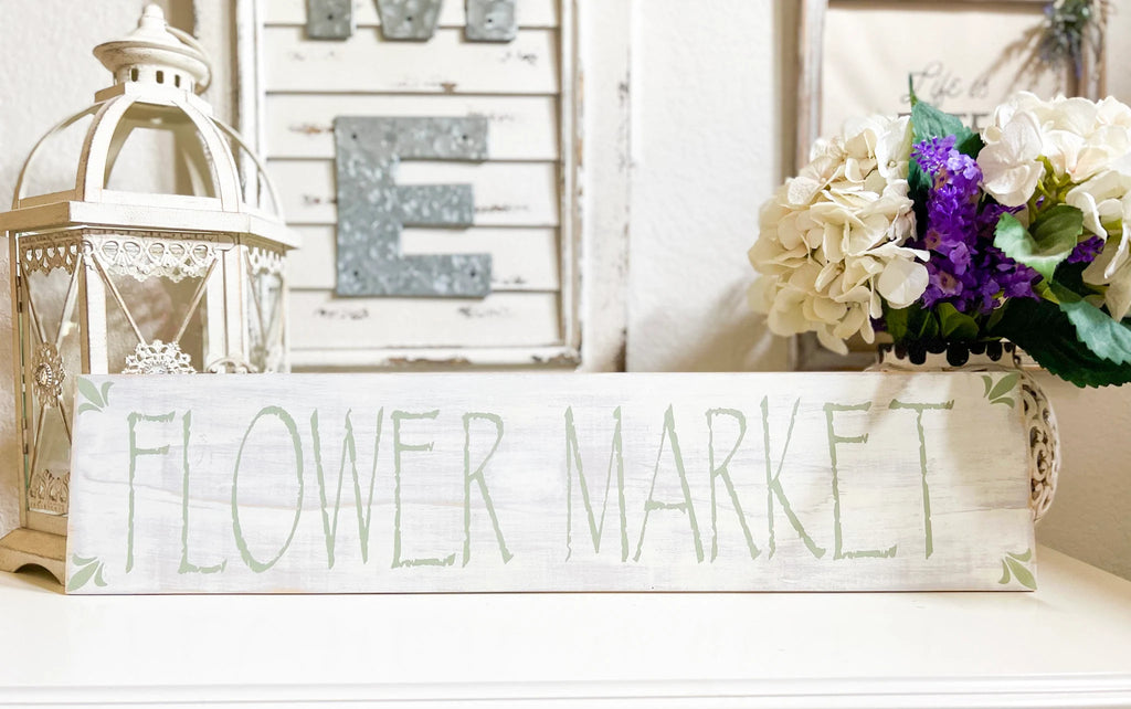 Flower Market sign on white mantle with white hydrangeas and purple flowers beside shutters