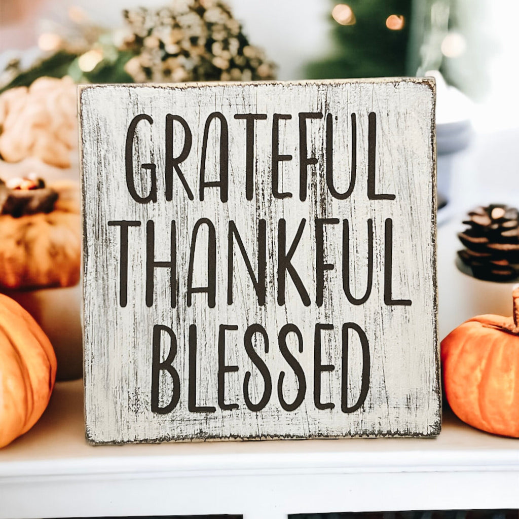 Grateful Thankful Blessed distressed white wood block sign on white tiered tray with Christmas tree and red berry stems