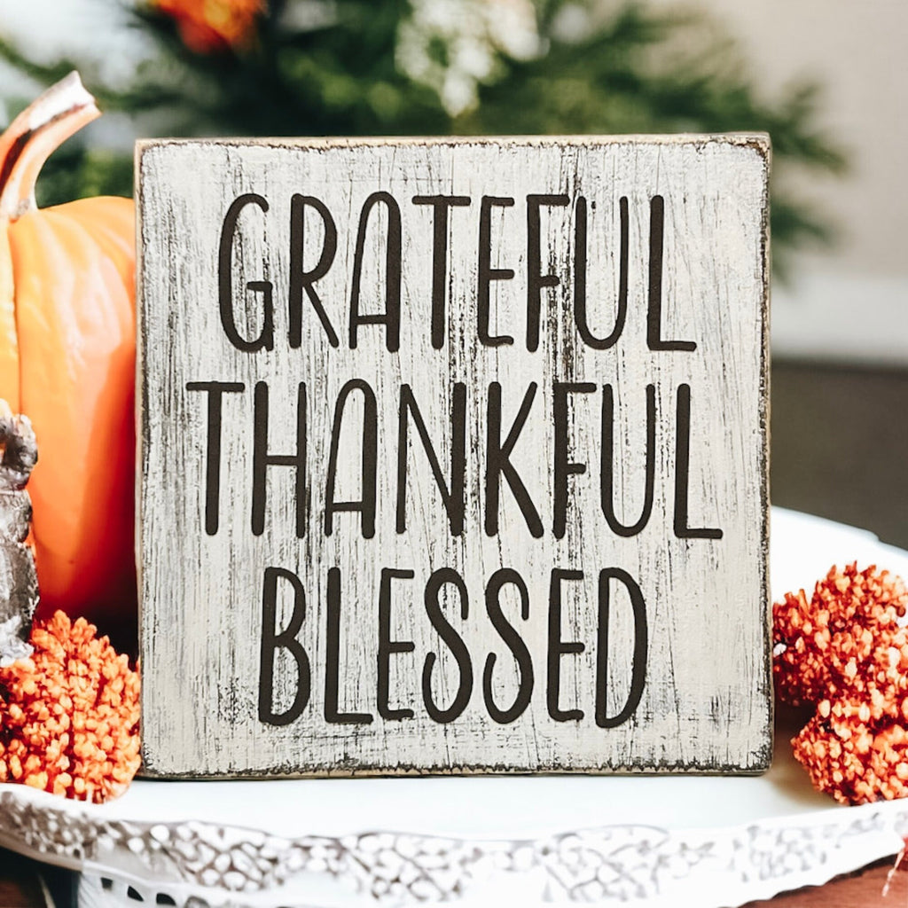 Grateful Thankful Blessed distressed white wood block sign on white fireplace mantel with orange and white pumpkins