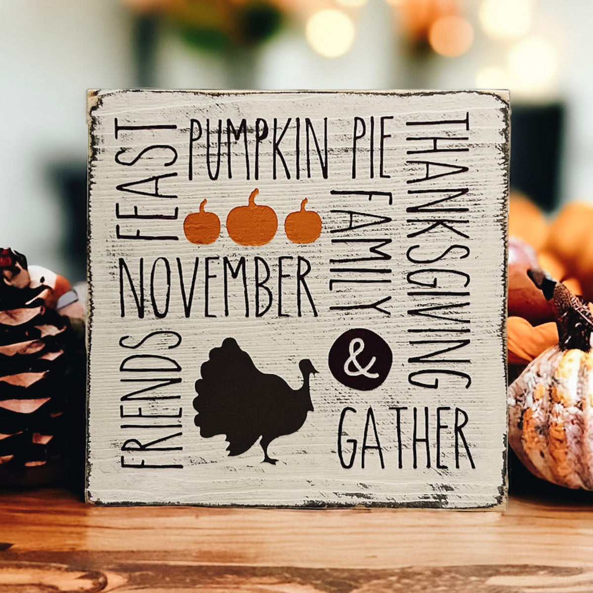 Thanksgiving farmhouse word collage wood block sign with turkey silhouette on holiday table setting with candles and red ornaments