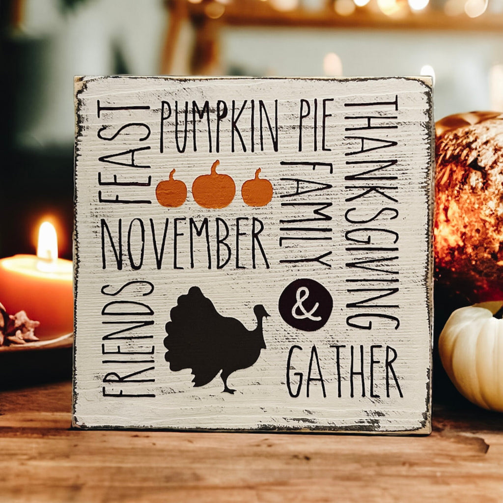 Thanksgiving farmhouse word collage wood block sign with turkey silhouette on rustic wood surface with pine cone and dried botanicals