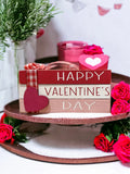 Happy Valentine's Day wood book stack with pine cones and red heart ornaments on white wood table